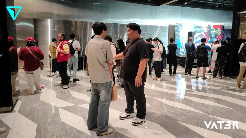 ชายสองคนยืนคุยกันในโถงจัดงานที่ทันสมัย ขณะที่ผู้ร่วมงานกำลังเข้าแถวใกล้จอดิจิทัลด้านหลัง