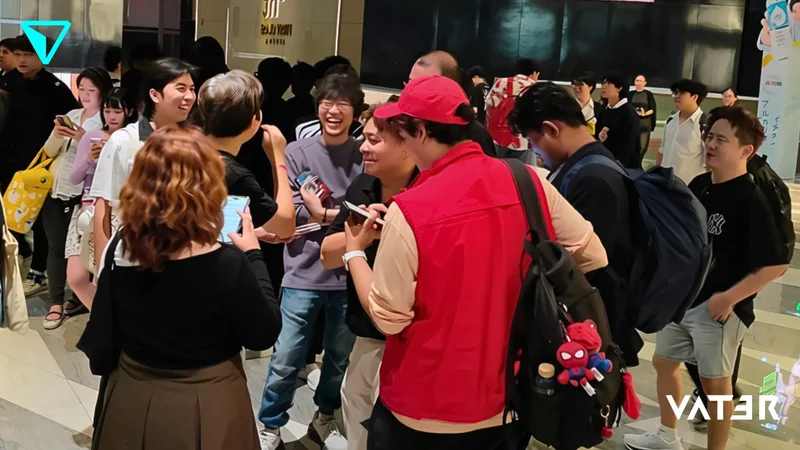 กลุ่มคนรุ่นใหม่กำลังพูดคุย ยิ้มแย้ม และถ่ายรูปด้วยกันอย่างสนุกสนานในโถงจัดงานที่มีผู้คนพลุกพล่าน
