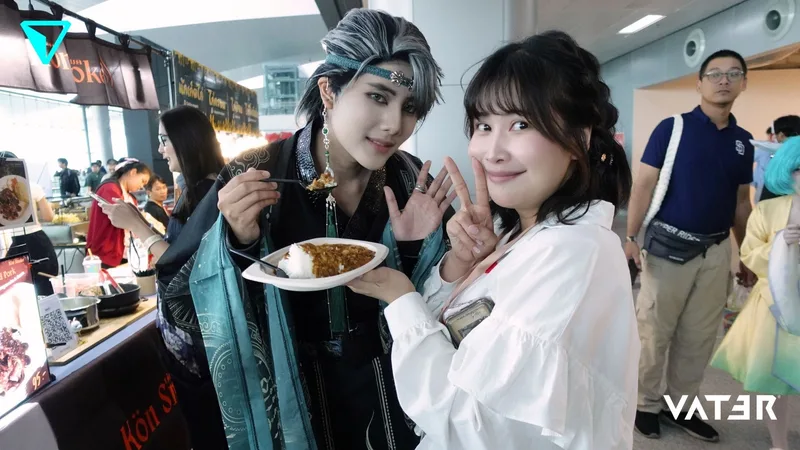 คอสเพลเยอร์ถือช้อนตักข้าวแกงกะหรี่โพสท่าคู่กับหญิงสาวยิ้มชูสองนิ้วที่ซุ้มอาหารในงานอีเวนต์