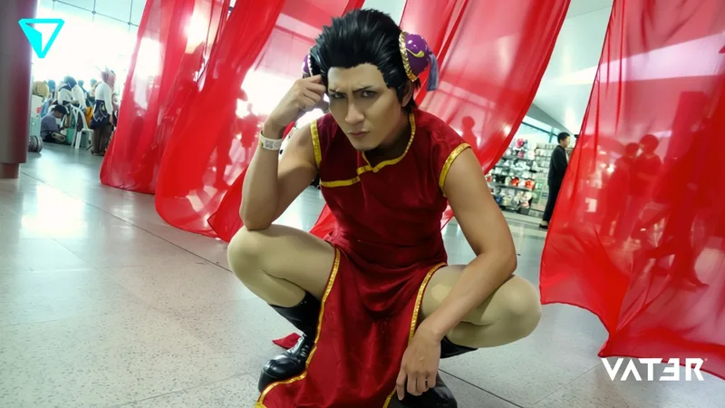 ชายคอสเพลย์เป็น Chun-Li ในชุดสีแดงกำลังนั่งยอง ๆ ระหว่างม่านผ้าสีแดงในงานอีเวนต์