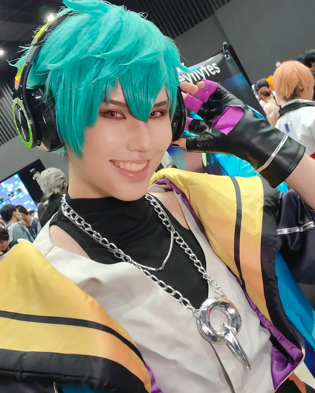 คอสเพลเยอร์ในชุด HEARTSTEEL Ezreal ยิ้มและโพสท่าในฮอลล์จัดงานคอนเวนชันที่เนืองแน่นไปด้วยผู้คน