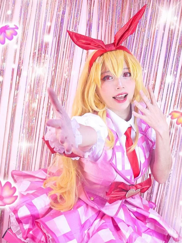 คอสเพลเยอร์ในชุด Ichigo Hoshimiya ยื่นมือมาข้างหน้าหน้าม่านประกายสีชมพูสดใส