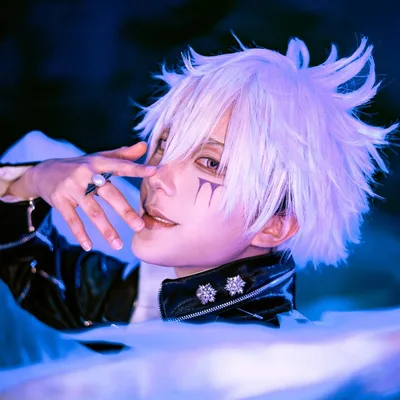 คอสเพลเยอร์ในชุด Byakuran จาก Katekyo Hitman Reborn! โพสท่าท่ามกลางปีกสีขาวและยกมือแตะใบหน้าใต้แสงไฟสีน้ำเงิน