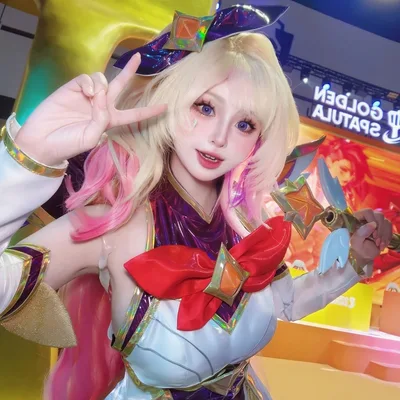 คอสเพลเยอร์ในชุด Star Guardian Seraphine โพสท่าชูสองนิ้วและถือคทาในงานเกม Golden Spatula