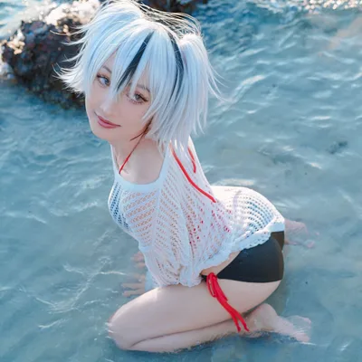 คอสเพลเยอร์ในชุด Summer Jeanne Alter จาก Fate/Grand Order คุกเข่าอยู่ในน้ำทะเลใสริมโขดหิน