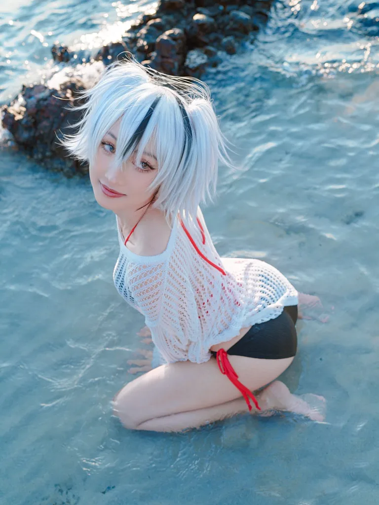 คอสเพลเยอร์ในชุด Summer Jeanne Alter จาก Fate/Grand Order คุกเข่าอยู่ในน้ำทะเลใสริมโขดหิน