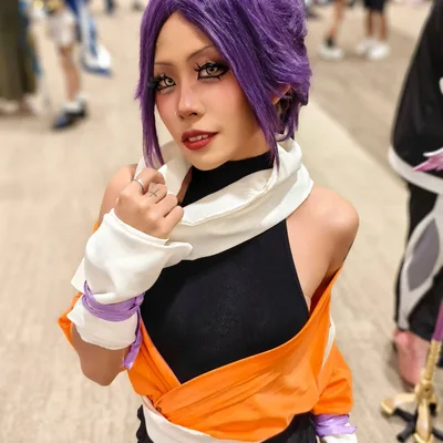 คอสเพลเยอร์แต่งกายเป็น Yoruichi Shihouin จาก Bleach ด้วยวิกผมสีม่วงและชุดสีส้มดำ โพสท่าในงานอีเวนต์