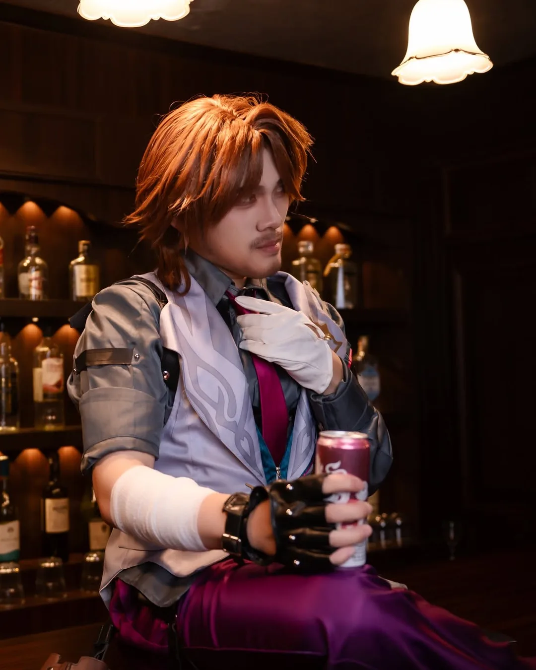 คอสเพลเยอร์ในบท Gallagher จาก Honkai: Star Rail ถือกระป๋องเครื่องดื่มพลางจัดเนคไทที่เคาน์เตอร์บาร์ไฟสลัว