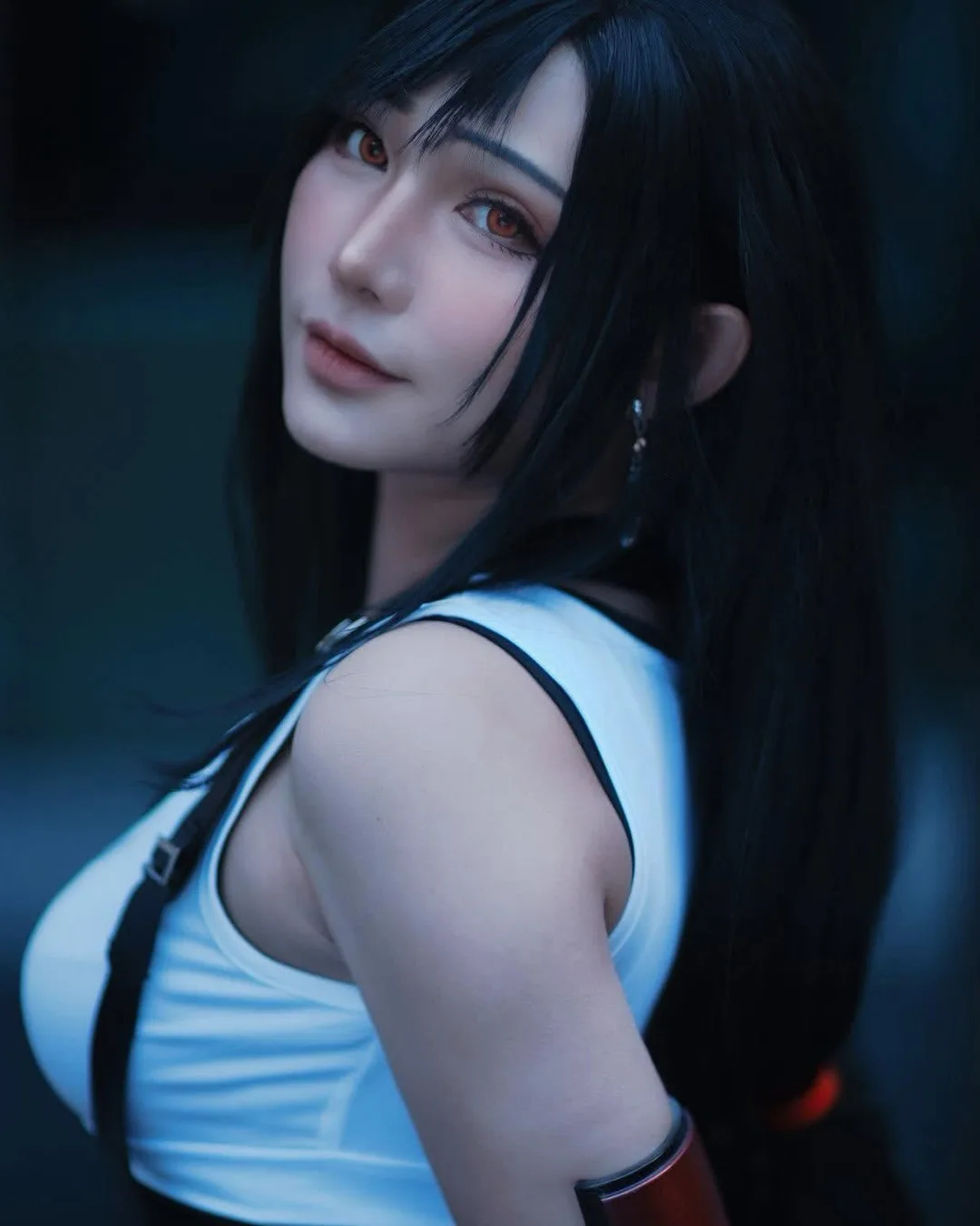 คอสเพลเยอร์แต่งกายเป็น Tifa Lockhart จาก Final Fantasy VII หันมองข้ามไหล่ในชุดเสื้อกล้ามสีขาวและสายเอี๊ยม