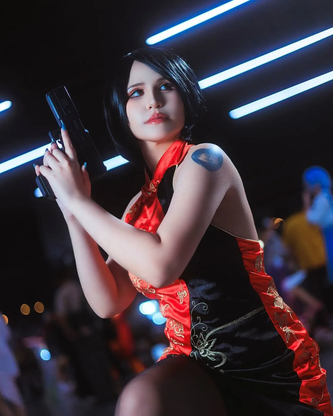 คอสเพลเยอร์ในชุด Ada Wong จาก Resident Evil โพสท่าถือปืนพกใต้แสงไฟนีออนในงานอีเวนต์