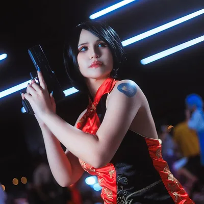 คอสเพลเยอร์ในชุด Ada Wong จาก Resident Evil โพสท่าถือปืนพกใต้แสงไฟนีออนในงานอีเวนต์