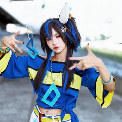 คอสเพลเยอร์แต่งกายเป็น Daitaku Helios จาก Uma Musume Pretty Derby ในเสื้อสีน้ำเงินเหลือง กำลังโพสท่าสไตล์ฮิปฮอปกลางแจ้ง