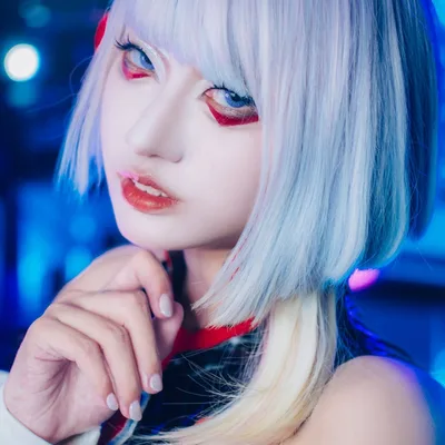 คอสเพลเยอร์แต่งเป็น Lucy จาก Cyberpunk: Edgerunners สวมวิกผมบ็อบสีฟ้าและแต่งตาโทนแดง โพสท่าหน้าแสงไฟนีออนสีน้ำเงิน
