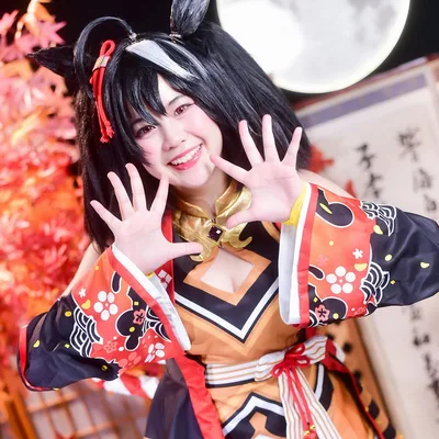 คอสเพลเยอร์ในชุด Kitasan Black จาก Uma Musume ยิ้มสดใสและยกสองมือขึ้นโพสท่าหน้าฉากหลังใบไม้เปลี่ยนสีและพระจันทร์เต็มดวง
