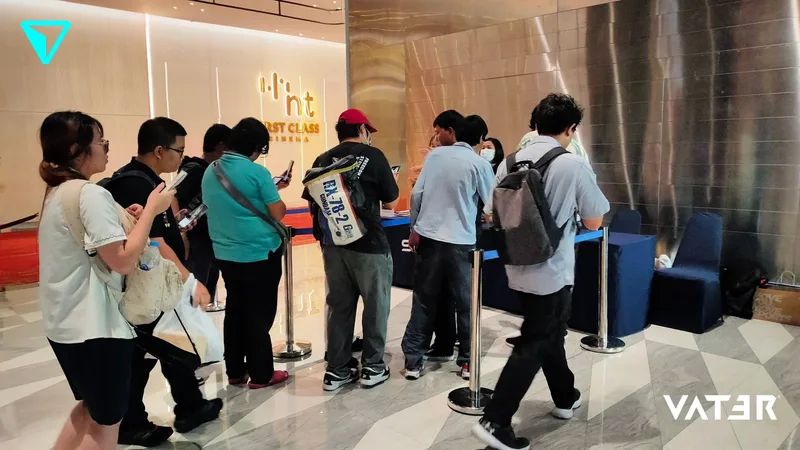 ผู้เข้าร่วมงานยืนต่อแถวที่จุดลงทะเบียนบริเวณหน้าทางเข้าโรงภาพยนตร์