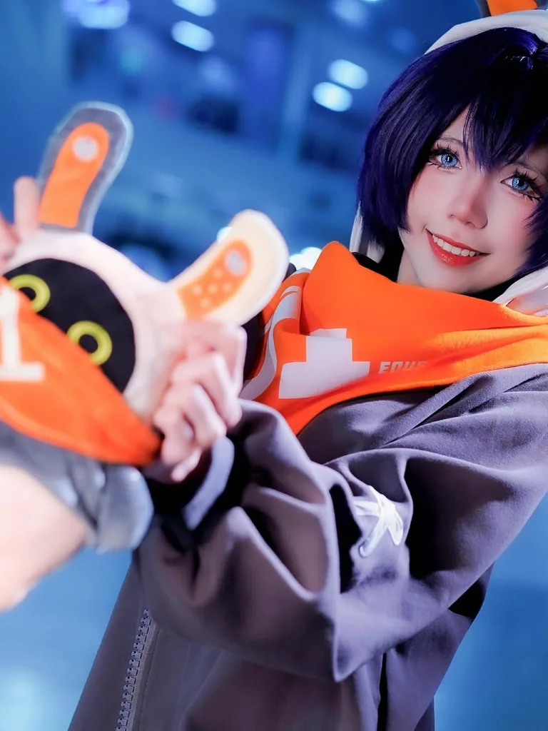 คอสเพลเยอร์แต่งเป็น Belle จาก Zenless Zone Zero ยิ้มและถือตุ๊กตา Bangboo Eous ในงานอีเวนต์ในร่ม