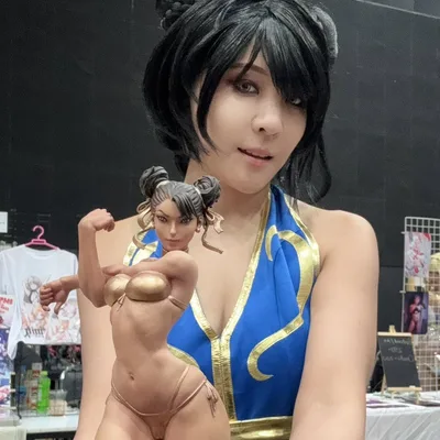 คอสเพลเยอร์ในชุด Chun-Li ถือฟิกเกอร์ของตัวละครในชุดบิกินีสีทองที่งานจัดแสดง