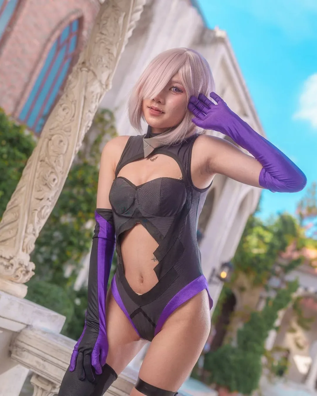คอสเพลเยอร์ในชุด Mash Kyrielight จาก Fate/Grand Order โพสท่ากลางแจ้งในชุดบอดี้สูทสีดำผ่าเว้าและถุงมือยาวสีม่วง