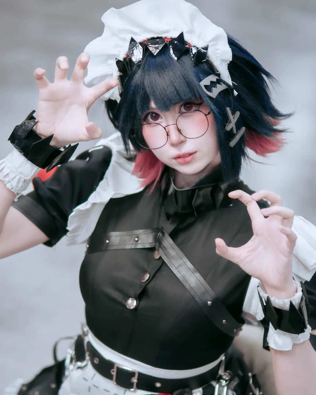 คอสเพลเยอร์แต่งกายเป็น Ellen Joe จาก Zenless Zone Zero โพสท่ากางมือคล้ายกรงเล็บอย่างขี้เล่นในชุดเมดสไตล์กอทิกพร้อมสวมแว่นตา