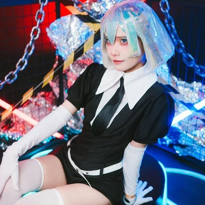 คอสเพลเยอร์ในชุดตัวละคร Diamond จาก Land of the Lustrous นั่งอยู่ในสตูดิโอที่ประดับไฟนีออนและโซ่
