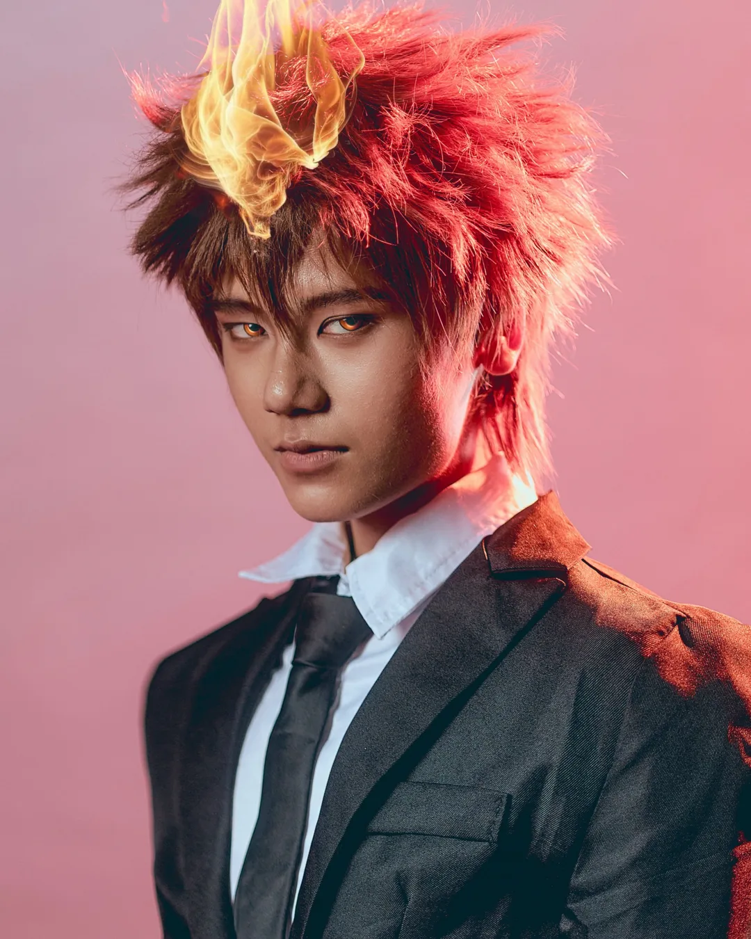 คอสเพลเยอร์แต่งกายเป็น Tsunayoshi Sawada จาก Katekyo Hitman Reborn! พร้อมผมชี้ฟู เปลวไฟบนหน้าผาก และสวมชุดสูทสีดำ