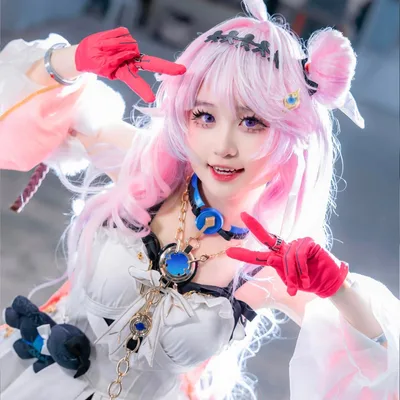 คอสเพลเยอร์ในชุด March 7th จาก Honkai: Star Rail โพสท่าชูสองนิ้วอย่างสดใสในงานอีเวนต์ในร่ม
