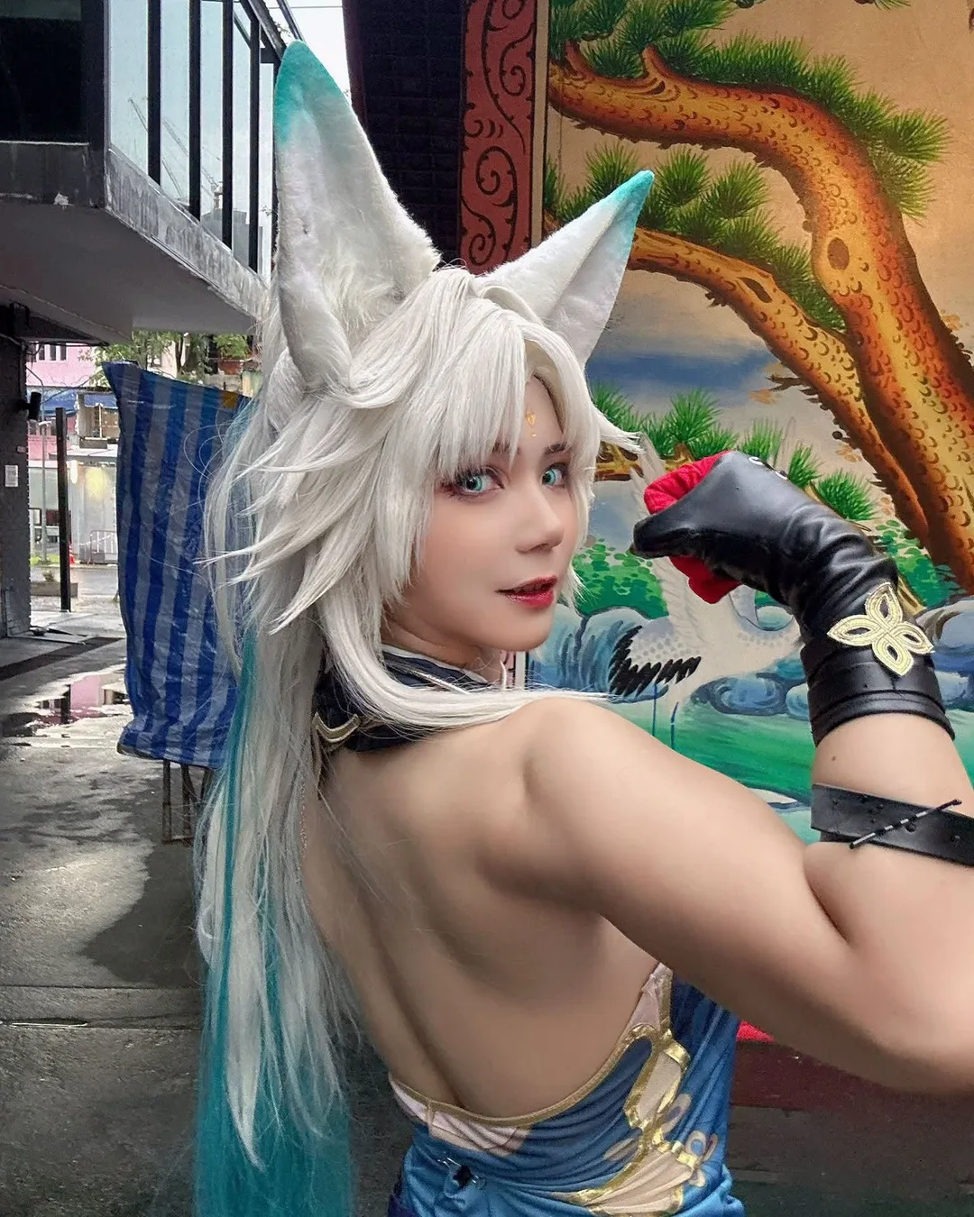 คอสเพลเยอร์ในชุด Feixiao จาก Honkai: Star Rail พร้อมหูจิ้งจอกสีขาวหันมองข้ามไหล่กลางแจ้ง