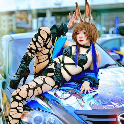 คอสเพลเยอร์สวมหูกระต่ายและถุงน่องขาดโพสท่าเอนตัวบนฝากระโปรงรถอิตาชะสีน้ำเงิน