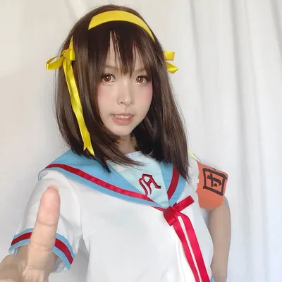 คอสเพลเยอร์แต่งกายเป็น Haruhi Suzumiya ในชุดกะลาสีสีฟ้าขาวชี้นิ้วมาทางกล้องหน้าฉากหลังสีขาว