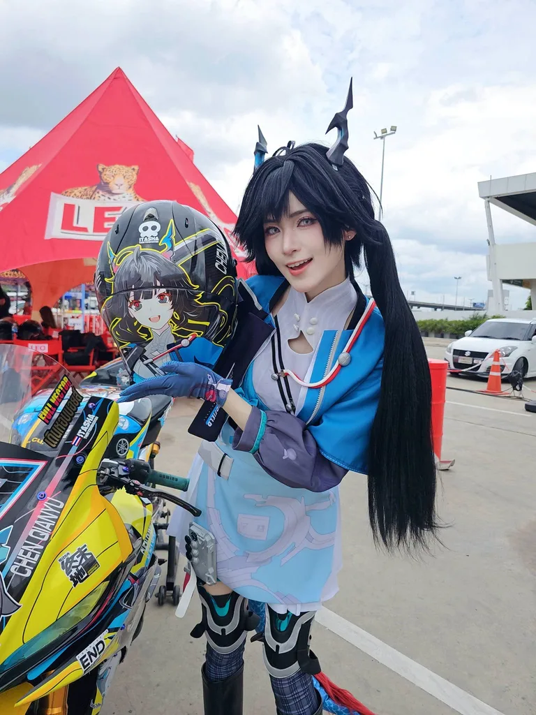 คอสเพลเยอร์ที่มีเขาและมัดผมแกละสีดำยืนโพสท่าข้างมอเตอร์ไซค์ พร้อมถือหมวกกันน็อกลายตัวละครอนิเมะ