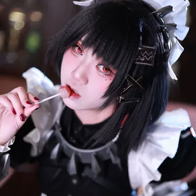 คอสเพลเยอร์ในชุด Ellen Joe จาก Zenless Zone Zero ถืออมยิ้มแตะที่ริมฝีปากในชุดเมดสไตล์โกธิก