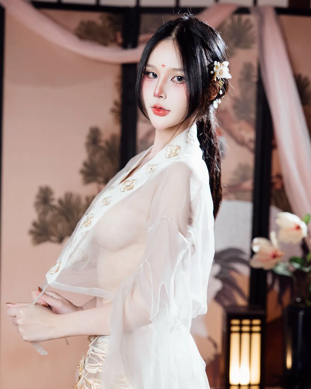 หญิงสาวในชุดฮั่นฝูผ้าโปร่งสีขาวปักลายพร้อมปิ่นปักผมลายดอกไม้ โพสท่าหน้าฉากกั้นห้องภาพวาดแบบดั้งเดิม