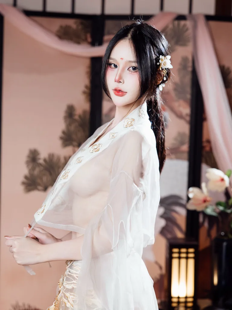 หญิงสาวในชุดฮั่นฝูผ้าโปร่งสีขาวปักลายพร้อมปิ่นปักผมลายดอกไม้ โพสท่าหน้าฉากกั้นห้องภาพวาดแบบดั้งเดิม