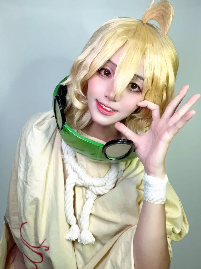 คอสเพลเยอร์แต่งกายเป็น Suika จาก Dr. STONE ยิ้มอย่างสดใสโดยมีหน้ากากแตงโมคล้องอยู่ที่คอ