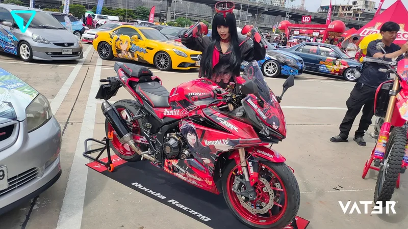 คอสเพลเยอร์ในชุดอนิเมะโพสท่าด้านหลังมอเตอร์ไซค์สปอร์ต Honda ลายอนิเมะสีแดงในงานมีตติ้งรถอิตาฉะกลางแจ้ง