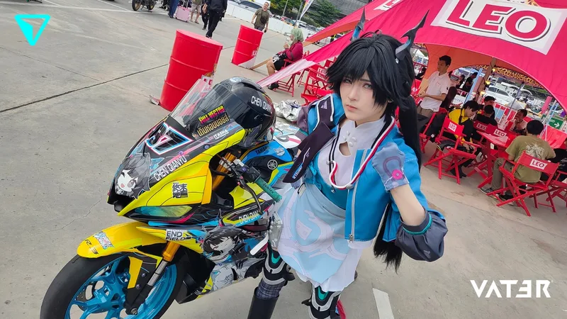 คอสเพลเยอร์สวมเขาและแจ็กเก็ตสีฟ้าโพสท่าข้างมอเตอร์ไซค์สปอร์ตสีเหลือง-ฟ้าลายอนิเมะในงานกลางแจ้ง