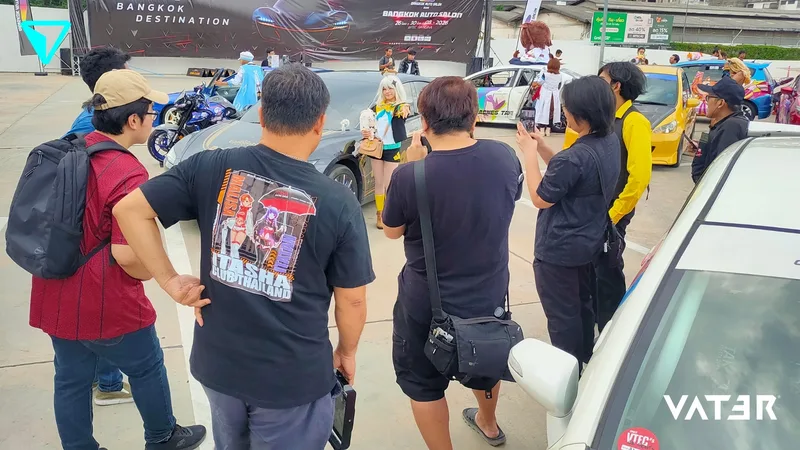 กลุ่มผู้ร่วมงานกำลังถ่ายภาพคอสเพลเยอร์ที่โพสท่าข้างรถยนต์ในงานรวมพลรถอิตาฉะกลางแจ้งในกรุงเทพฯ