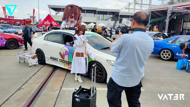 ช่างภาพกำลังถ่ายรูปคอสเพลเยอร์ที่ยืนโพสท่าข้างรถอิตาฉะตกแต่งลายอนิเมะในงานกลางแจ้ง