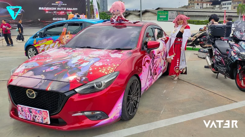 คอสเพลเยอร์ในชุด Yae Miko ยืนข้างรถยนต์ Mazda สีแดงลายอนิเมะอิตาฉะในงาน Bangkok Auto Salon
