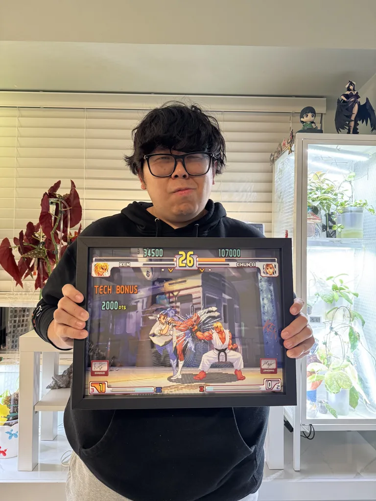 Justin Wong ถือกรอบรูป 3 มิติที่แสดงฉากการต่อสู้ชื่อดัง Evo Moment 37 จากเกม Street Fighter III: 3rd Strike