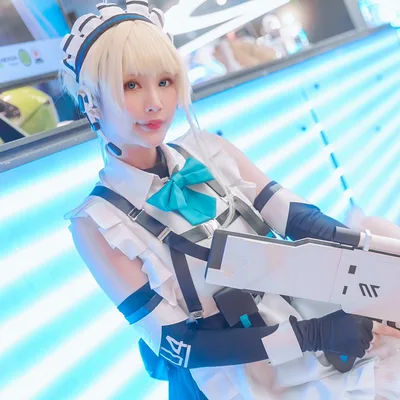 คอสเพลเยอร์ในชุด Toki จาก Blue Archive โพสท่าถือปืนพรอปสไตล์ล้ำยุคหน้าผนังไฟนีออนสีฟ้าในงานอีเวนต์