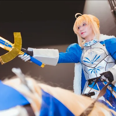 คอสเพลเยอร์แต่งกายเป็น Saber จากซีรีส์ Fate ถือดาบ Excalibur ขณะสวมชุดเกราะอัศวินสีน้ำเงินและสีเงิน