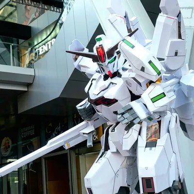 คอสเพลเยอร์ในชุดหุ่นยนต์ Gundam Calibarn สีขาวสุดอลังการ ยืนอยู่ท่ามกลางผู้ร่วมงานในฮอลล์จัดแสดง